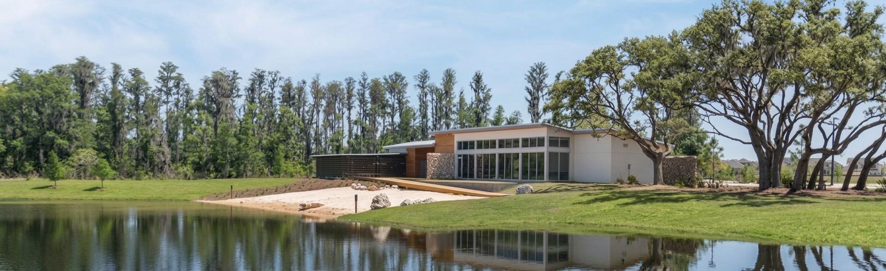 The Starkey Ranch amenity center seen across a calm pond, framed by cypress and live oak trees.